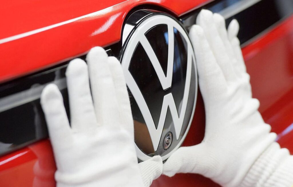 Một kỹ thuật viên gắn logo Volkswagen tại dây chuyền sản xuất các mẫu ô tô điện